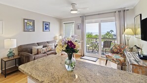 A living room with a large island, a sofa, and a chair. There is a balcony with a table and chairs. - Oceanfront Sea Cabin on the Front Beach of Isle of Palms (Isle Of Palms)