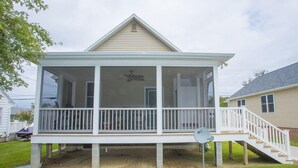 A two-story house with a covered porch, a staircase, and a satellite dish.