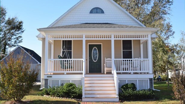 A single-story house with a front porch, a green door, and a small front yard.
