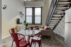 A modern living space with a dining area, a sofa, and a staircase. - Sosuite | 2BR Loft w W/D, Gym, Lounge (Philadelphia)