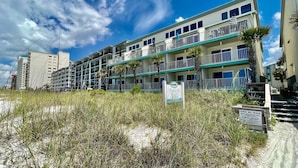A multi-story hotel with balconies, a sign indicating 'Nautical Watch', and a 'Leave No Trace' sign. - Gulf front 2 bedroom with stunning views & Free round of Golf Daily! (Panama City Beach)