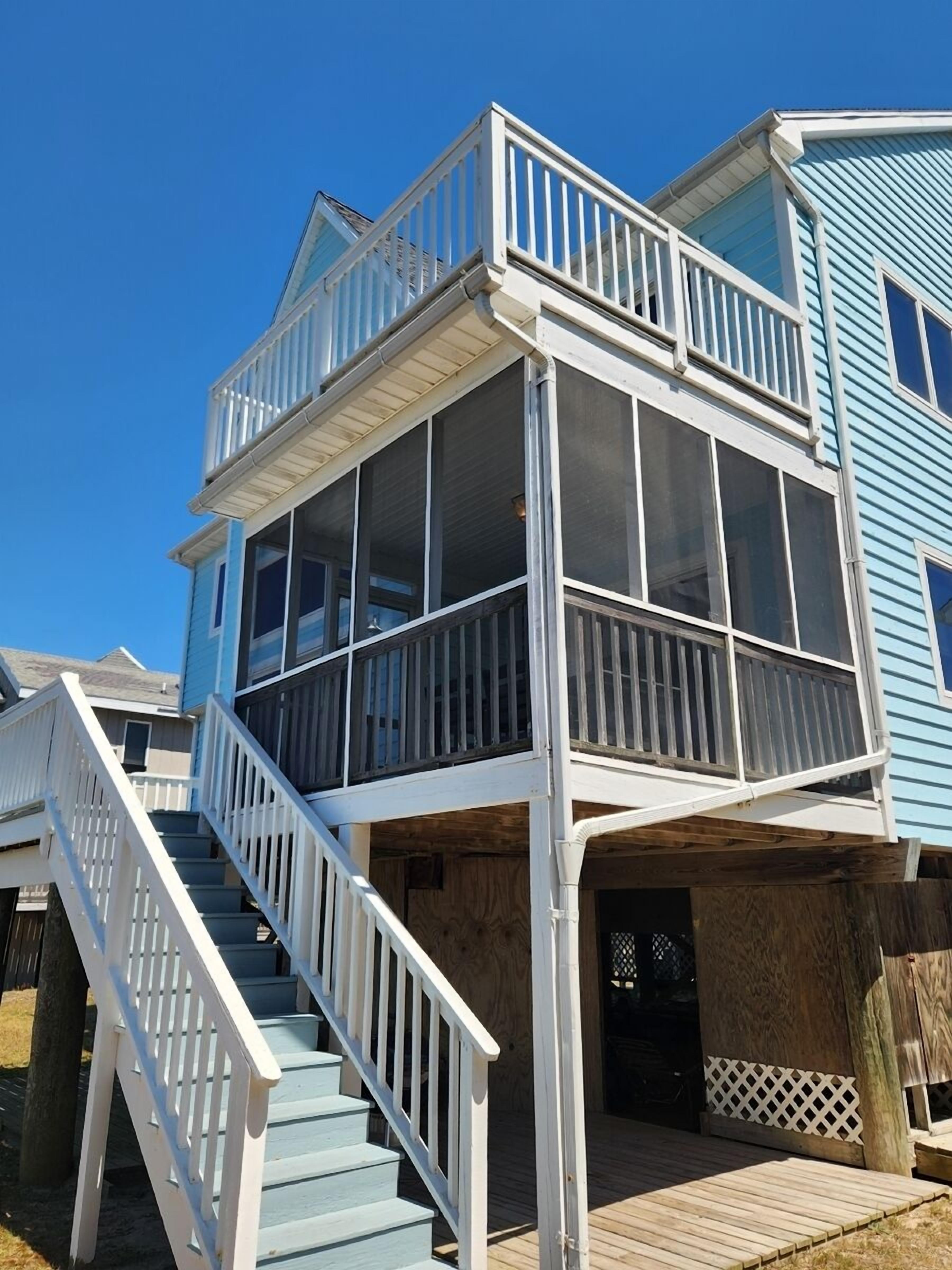 A two-story house with a wooden deck and a white staircase.