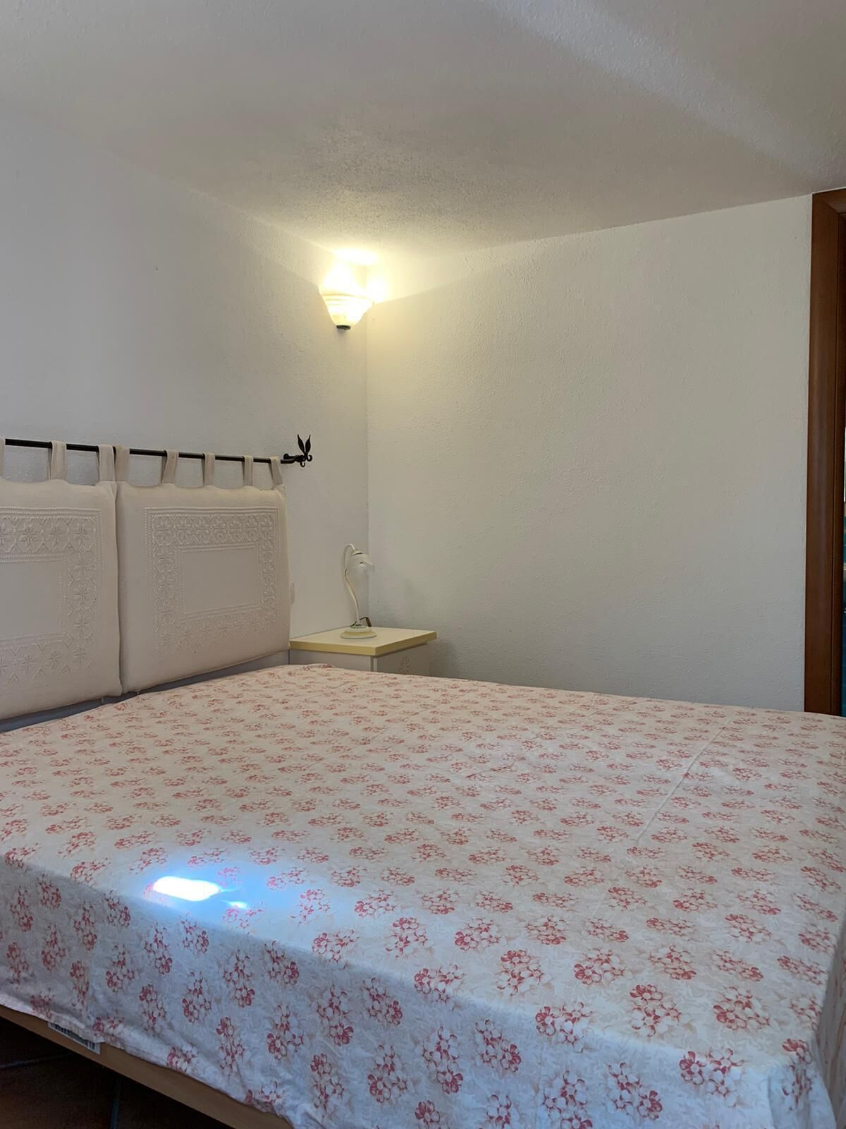 Une chambre à coucher avec un lit, une table de chevet et une lampe fixée au mur.