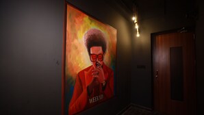 A hallway with a large poster on the wall, a door, and a light fixture.