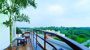 A balcony with a potted plant, a table, and a chair.
