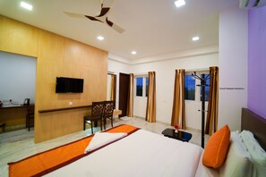 Une chambre d’hôtel équipée d’un lit, d’un bureau, d’une chaise, d’une télévision et d’un ventilateur de plafond.