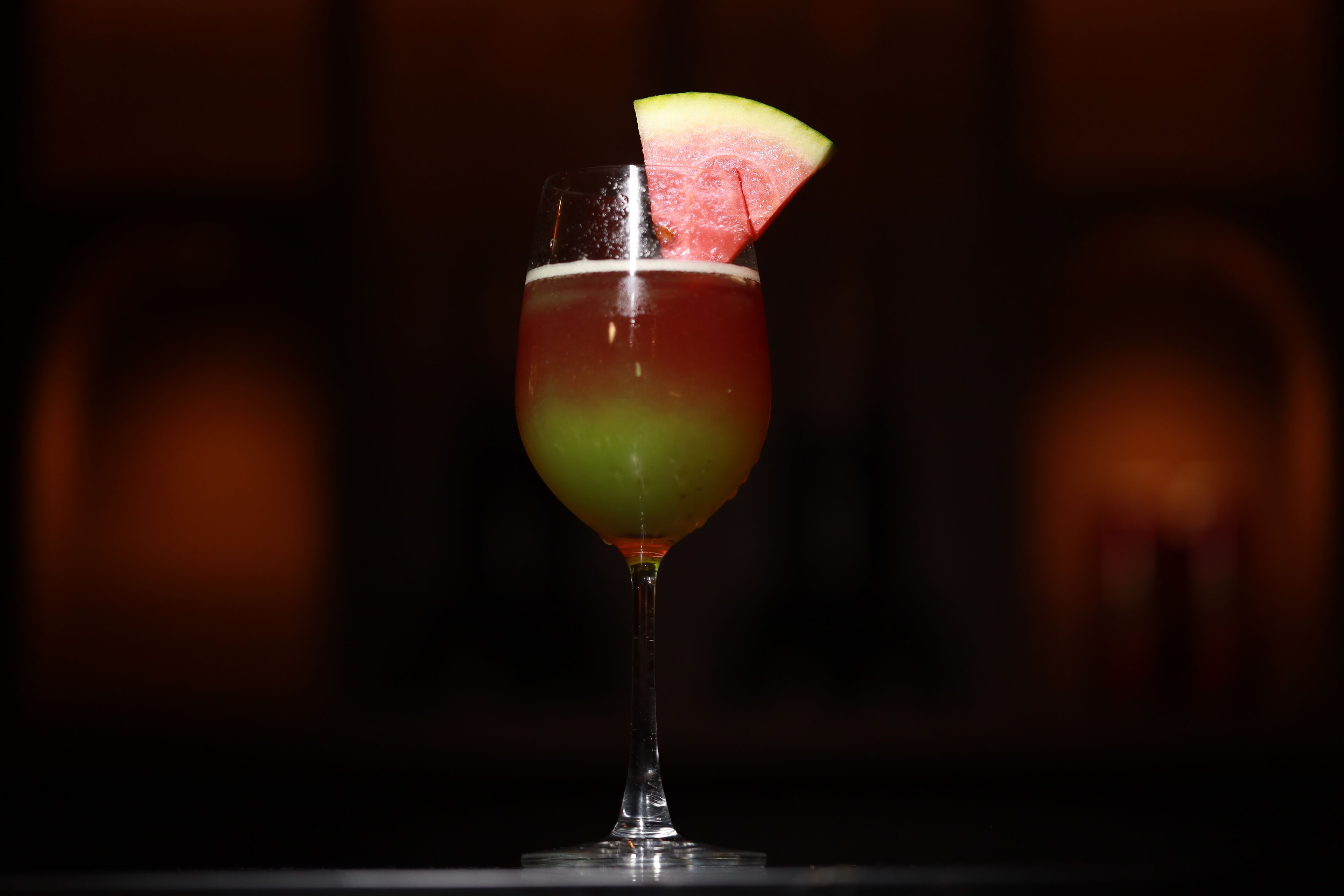 A cocktail with a slice of fruit garnish on a stemmed glass.