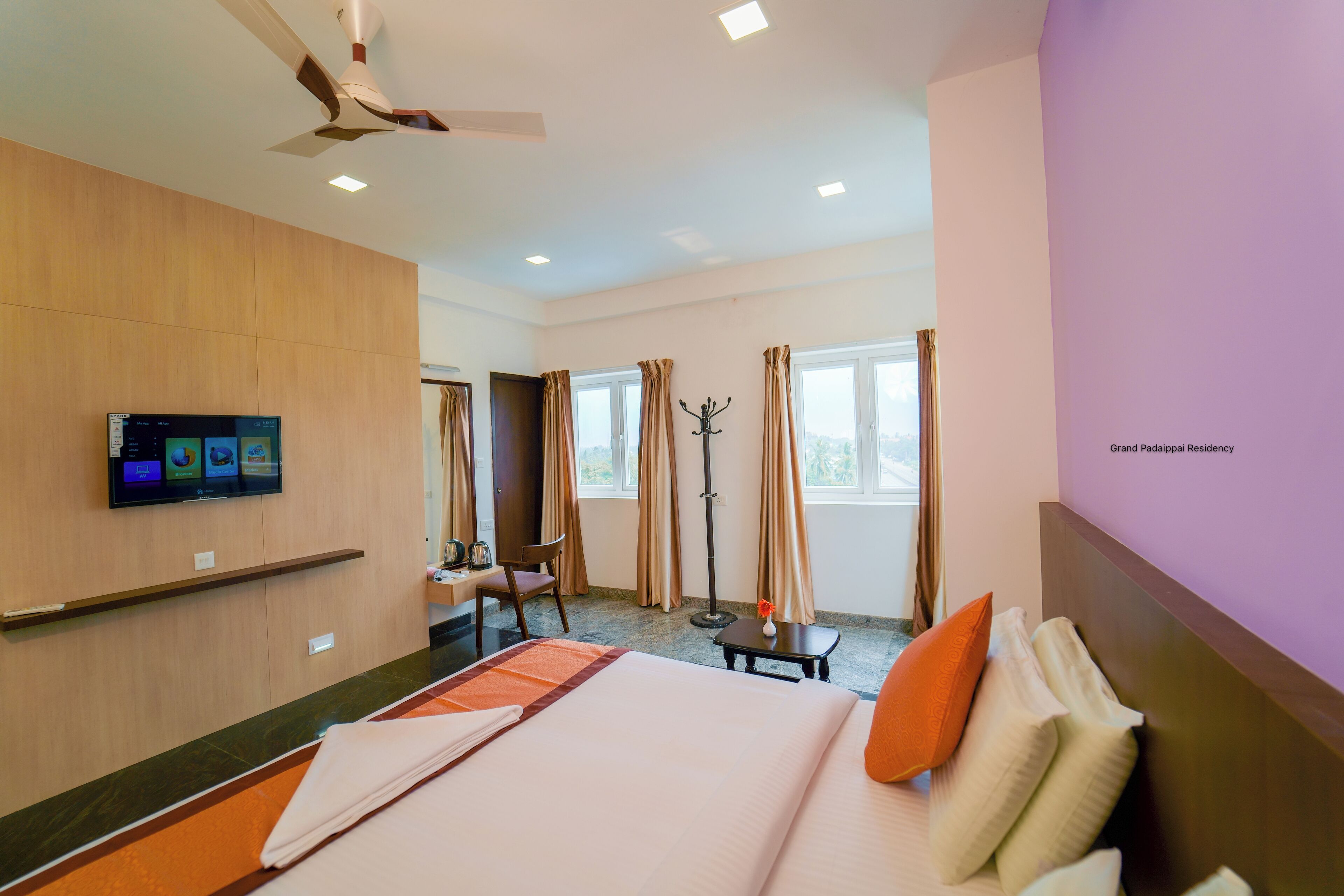 A hotel room with a bed, a desk, a chair, a television, and a window with curtains.