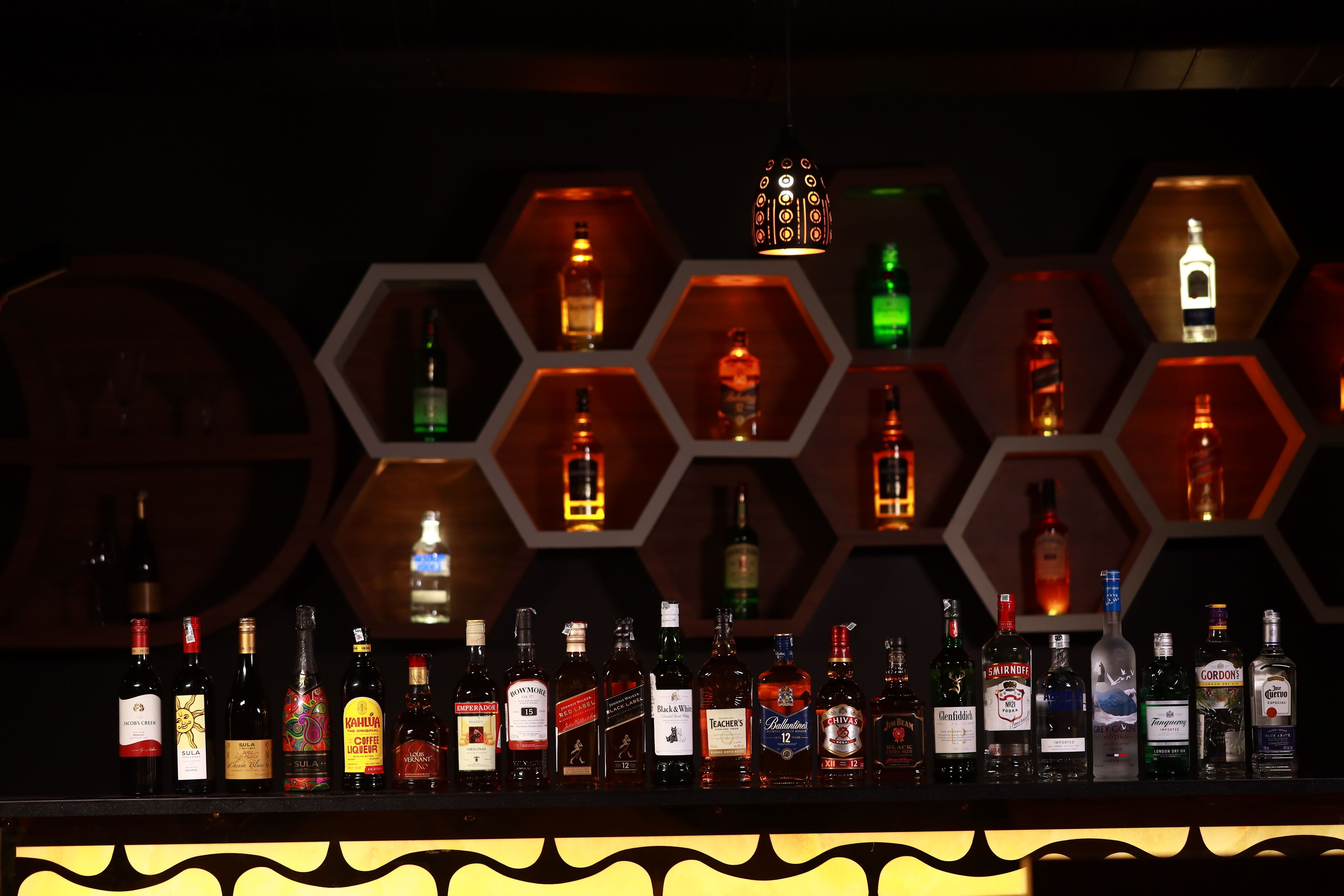 A bar with various bottles of liquor displayed in hexagonal shelves.
