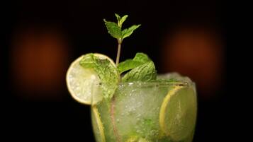 A glass of a green beverage with lime slices and mint leaves.
