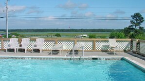 A swimming pool with lounge chairs and a view of a lighthouse in the distance.