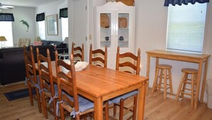 A dining area with a wooden table and chairs, a cabinet with glass doors, and a window with blinds.