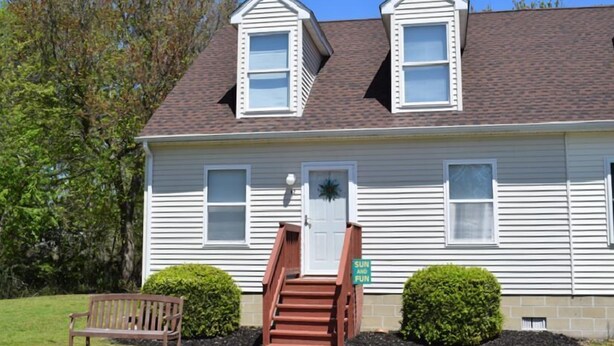 A two-story house with a front porch, a staircase, and a bench.