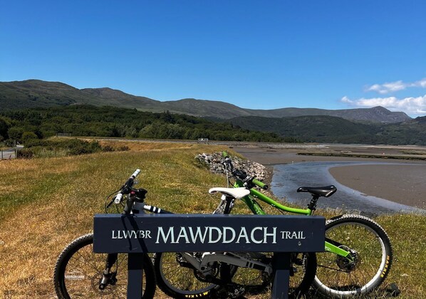 Una señal para el LLWYBR MAWDACH TRAIL con dos bicicletas estacionadas al lado.
