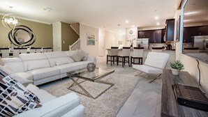 Ein modernes Wohnzimmer mit einem weißen Sofa, einem Glastisch und einem Essbereich mit einem weißen Stuhl und Tisch.