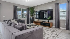 A modern living room with a large sectional sofa, a flat-screen TV, and a coffee table. - 8 Bedroom Movie Theater In Home Champions Gate! 8 Villa by RedAwning (Davenport)