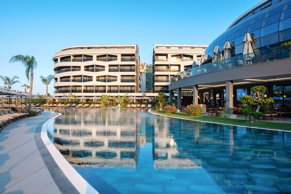 Un hotel moderno con una piscina grande, zona de estar al aire libre y un área de restaurante.