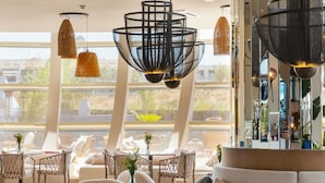 A modern lounge area with a curved ceiling, round tables, and a sofa with patterned cushions. - Liu Resorts - All inclusive (Manavgat)