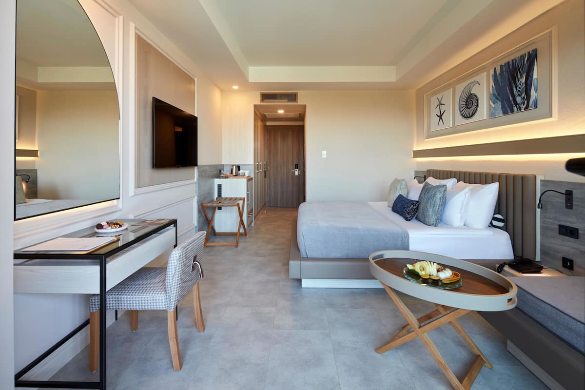 A modern hotel room with a bed, desk, chair, and a small dining table.