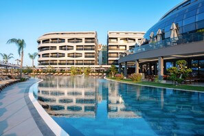 Un hotel moderno con una piscina grande, zona de estar al aire libre y un área de restaurante.