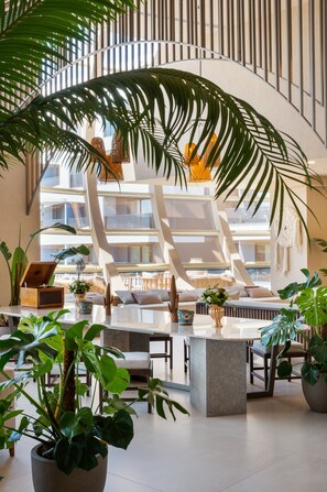 Een modern interieur met een centrale zithoek, grote ramen en diverse planten.