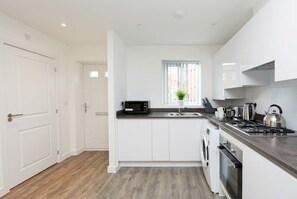 A modern kitchen with white cabinetry, a built-in oven, a microwave, and a gas stove.