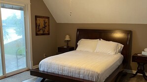 Un dormitorio con cama, ventilador de techo, mesita de noche y ventana.