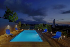 A rooftop swimming pool with blue chairs and a ladder, surrounded by a wooden deck and potted plants. - Villa  GGK (Σκεπαστή)