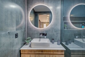 A modern bathroom with a rectangular sink, wooden vanity, and two round mirrors. - Villa  GGK (Σκεπαστή)