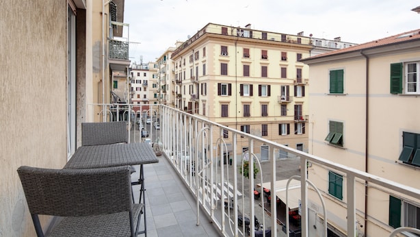 A balcony with wicker furniture, a railing, and a view of adjacent buildings. - Suites Colombo 32 (La Spezia)