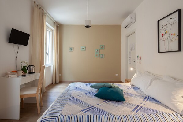 A bedroom with a bed, a desk, a chair, a TV, and a window. - Suites Colombo 32 (La Spezia)