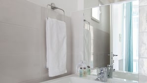 A bathroom with a white sink, a mirror, and a towel rack. - Suites Colombo 32 (La Spezia)