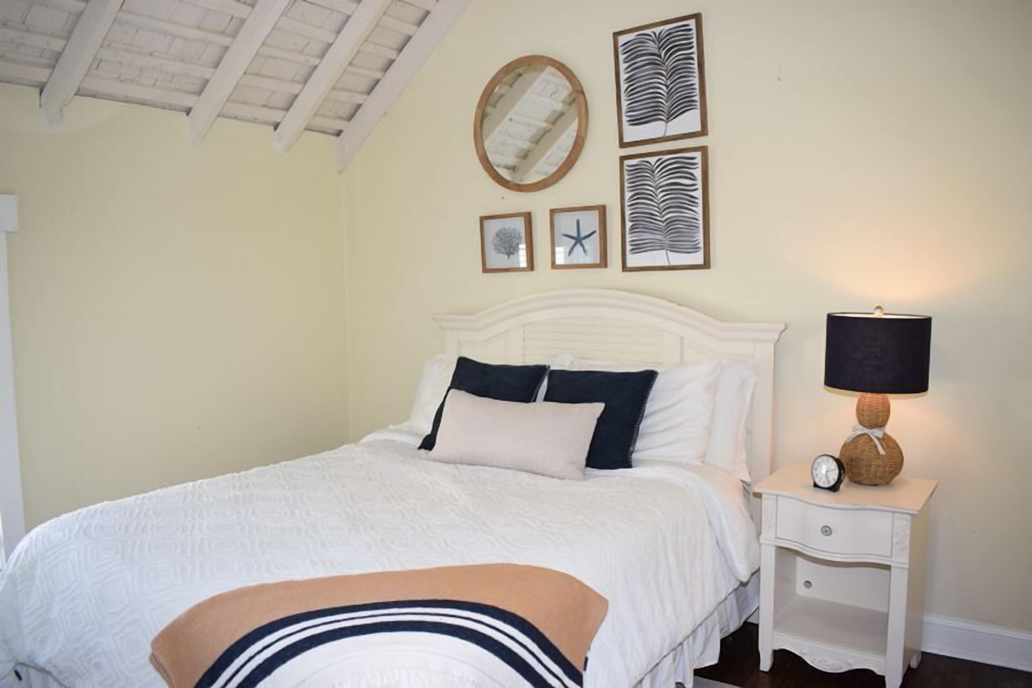 Une chambre à coucher avec un lit, une table de chevet avec une lampe et des œuvres d’art murales.