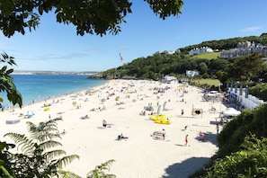 Una playa concurrida con gente, tiendas de campaña y kayaks.
