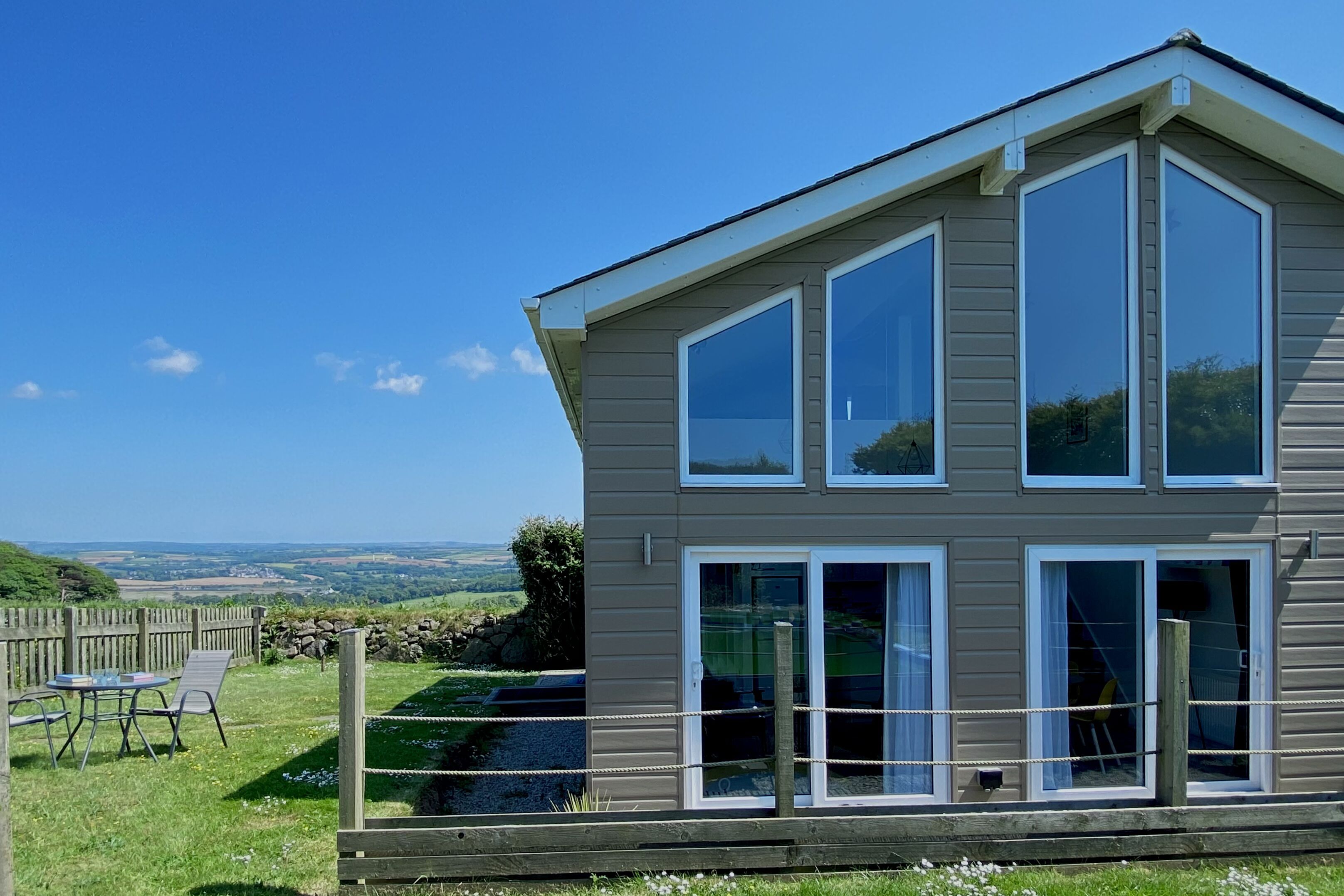 A two-story house with large windows and a view of the countryside.
