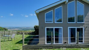 Ein zweistöckiges Haus mit großen Fenstern und Blick auf die Landschaft.