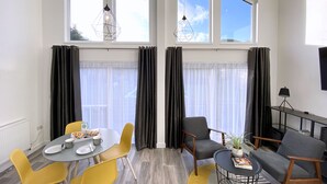 Ein stilvoller Essbereich mit einem Tisch für zwei Personen, gelben Stühlen und einem grauen Sofa.