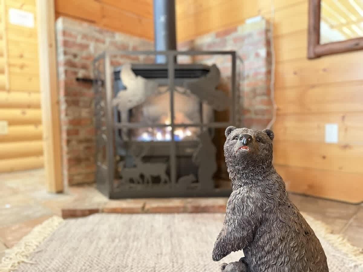 A bear figurine in a wooden cabin with a fireplace.