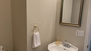 Ein Badezimmer mit Toilette, Waschtisch, einem Spiegel mit goldener Rahmen und einem gelben Mülleimer.
