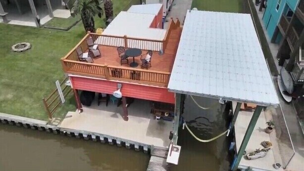 Une maison située au bord de l’eau, dotée d’une terrasse, d’un patio couvert et d’un petit quai pour bateaux.