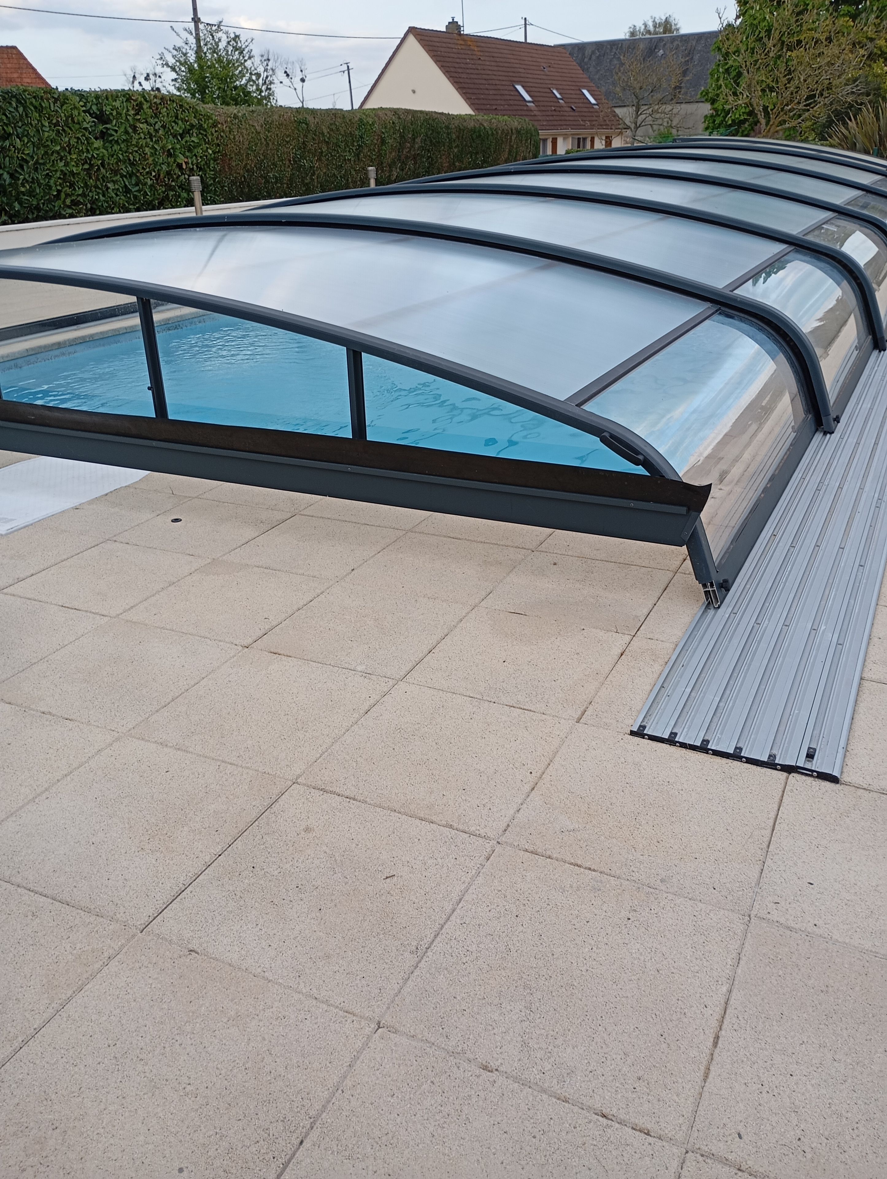 A swimming pool with a glass enclosure and metal railings.