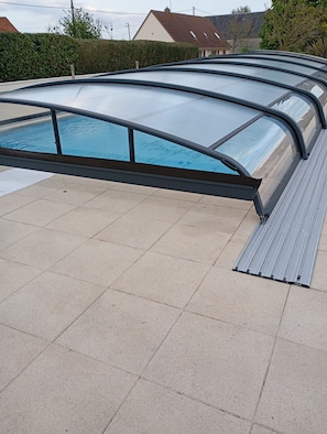 A swimming pool with a glass enclosure and metal railings. - Villa des Champs (Graignes-Mesnil-Angot)