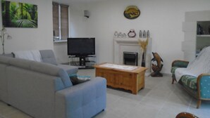 A living room with a grey sofa, a wooden coffee table, a television on a stand, a fireplace, and a decorative bird sculpture.