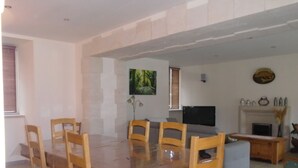 A spacious living room with a wooden dining table and chairs, a flat-screen TV, and a fireplace.