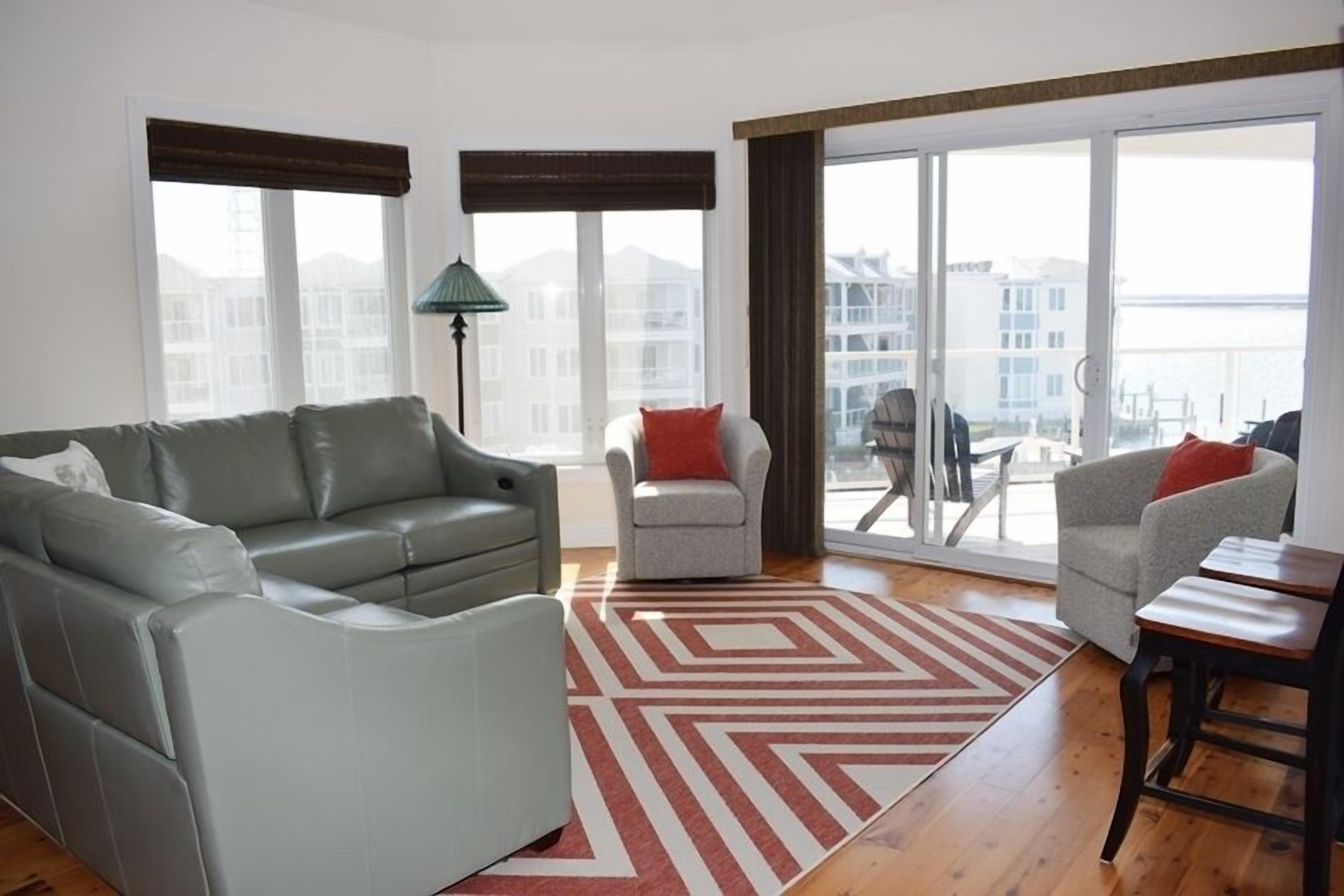 Una sala de estar moderna con un sofá gris, un sillón gris y un tapete estampado en rojo y blanco.