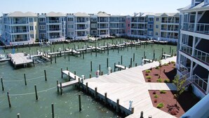 Una marina con barcos amarrados, un muelle de madera y edificios de varios pisos con balcones.