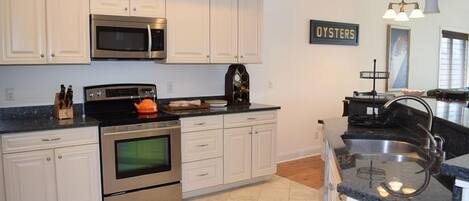 A modern kitchen with white cabinets, stainless steel appliances, and a black countertop.