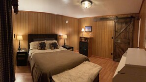 Une chambre à coucher avec un grand lit, deux tables de chevet avec des lampes, une commode et une porte en bois.