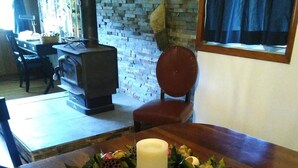 Une table de salle à manger en bois, agrémentée d’un centre de table composé de fruits et d’une bougie.