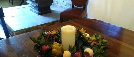 Una mesa de madera con un centro de frutas y una vela.